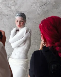 Model posing with white body paint while two photographers take pictures