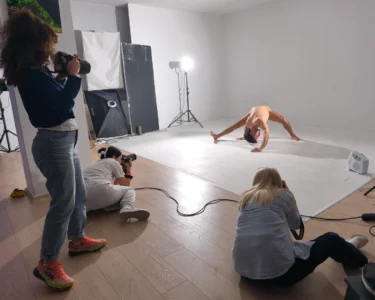 Photographers shoot a contortionist posing in a studio