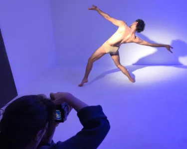 Photographer taking a picture of a dancer posing in a studio with blue lighting