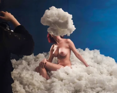 Nude woman seated in a cloud-filled scene with a cloud covering her head