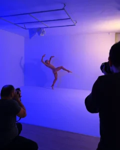 Dancer posing in a studio while two photographers take pictures