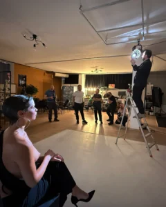 Photo shoot in progress with a seated model and several photographers in a studio