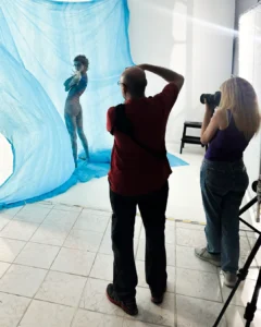 Photographers taking pictures of a model posed behind a translucent blue fabric backdrop